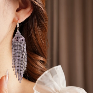 Macro detail of bohemian fan-shaped earrings with purple tassels and sparkling rhinestones