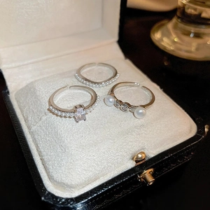 Close-up of three silver star rings with pearls and zircon in a black jewelry box