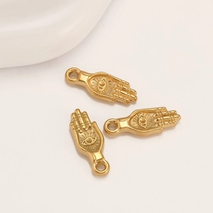 Macro detail of 18k gold plated Hamsa Hand charms with evil eye engraving for DIY jewelry
