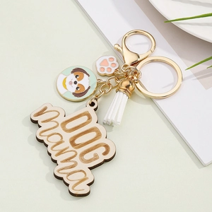 Detail of Dog Mama wooden keychain with white tassel, dog charm, and golden clasp