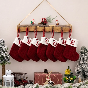Detail of red knit Christmas stockings hanging on a wooden rack with Welcome embroidery