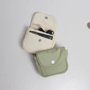 Detail of canvas mini coin purses in cream and light green showing snap buttons and pockets
