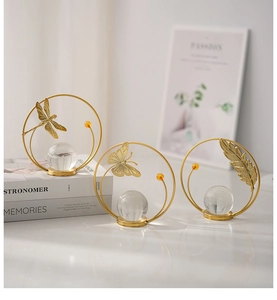Close-up of golden metal ornaments with dragonfly and crystal ball on marble desk