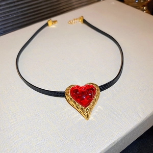 Macro detail of vintage red heart pendant with gold pleated frame on black choker cord