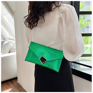 Dettaglio pochette verde con motivo a serpente, catena dorata e fibbia in metallo
