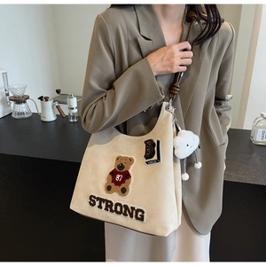 Dettaglio della borsa tote beige in pelle scamosciata con patch orso e pendente nuvola