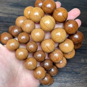 Macro shot of natural wood prayer beads with dark brown wave grain and polished finish