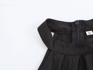Detail of elegant black halter dress featuring seamless back zipper and size S label