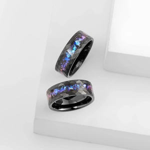 Detailed macro view of black faceted titanium steel ring with iridescent galaxy shell inlay