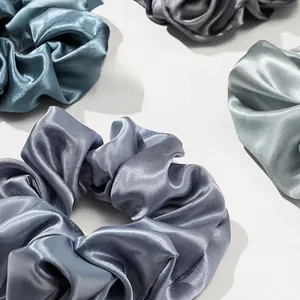 Macro detail of silk-like satin scrunchies showing smooth texture and elegant folds