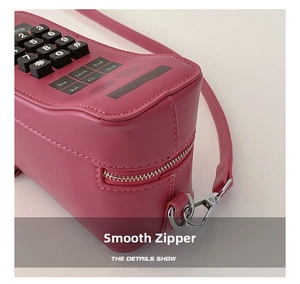 Detail view of the smooth silver zipper and pink leather on phone-shaped crossbody bag