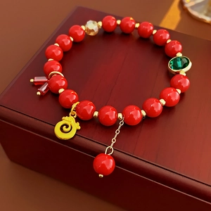 Détail d'un bracelet de perles rouges festives avec un pendentif dragon doré et un pompon