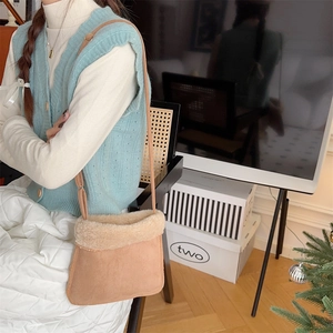 Détail d'un sac bandoulière en daim marron avec bordure en fausse fourrure crème style hiver
