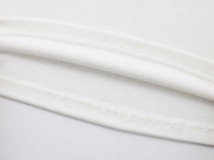 Détail d'un t-shirt blanc en coton montrant l'ourlet à double couture et la doublure polaire