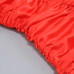 Nahaufnahme von rotem Satinstoff mit elastischen Falten-Details an einem Kleid