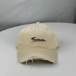 Détail de la casquette beige avec bords effilochés et broderie Fantastic raffinée