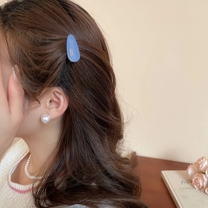 Détail de la pince à cheveux en acrylique bleu et accessoires en perles sur modèle