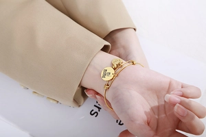 Détail de breloques cœur dorées gravées Love mi mama sur un bracelet en acier flexible