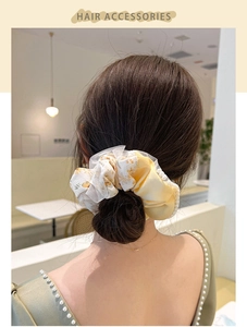 Detail of floral scrunchie with pearl trim on a low bun hair style for women