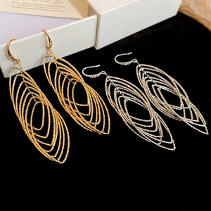 Détail de boucles d'oreilles ovales évidées en or et argent avec texture de sable étincelant