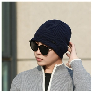 Detail view of a navy blue ribbed knit beanie with a small logo plate and thermal lining