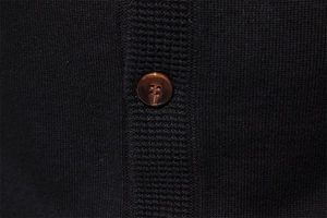 Close-up of black knitted fabric texture with a polished brown round button detail