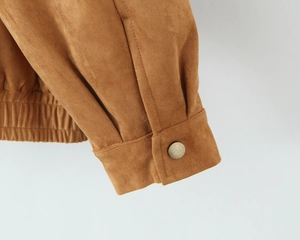 Detailed close-up of brown suede jacket cuffs with bronze buttons and elastic waistband