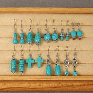 Close-up of bohemian turquoise earring set with vintage silver accents in a wooden display tray
