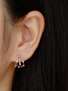 Macro shot of a silver layered hoop earring with sparkling rhinestones worn on ear