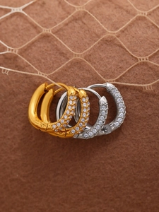 Macro shot of U-shaped gold and silver earrings featuring triple-row pave white zircon