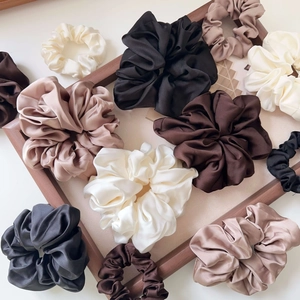 Close-up of premium satin scrunchies in neutral earth tones on a wooden tray