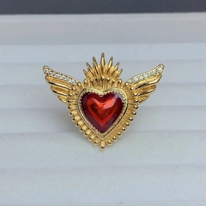 Macro shot of gold-plated heart ring with wings, red enamel, and zircon details