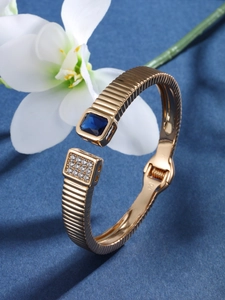 Detail of gold-plated hinged bangle with blue square gemstone and white zircon stones