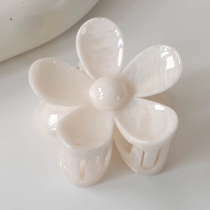Détail macro de la pince à cheveux fleur en acétate blanc crème avec texture marbrée