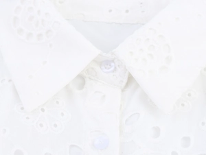 Detail of the white lapel collar with button and delicate floral hollow embroidery
