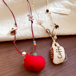 Detail of fabric pendant necklace with beaded red apple and embroidered coffee cup charms
