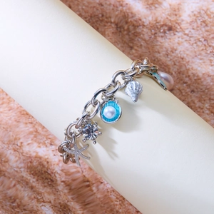 Detail of silver ocean-themed bracelet with blue enamel shells and starfish charms