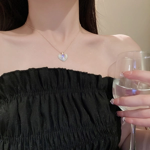 Detail of elegant gold heart pendant necklace worn by model in a sophisticated setting