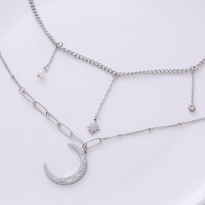 Layered silver crescent moon necklace with star and pearl accents on white background