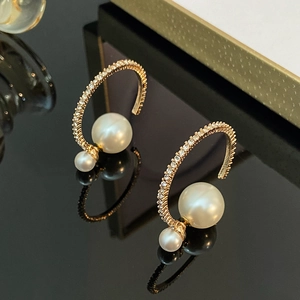 Exaggerated C-shaped gold hoop earrings with sparkling rhinestones and white pearls