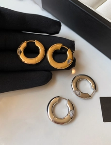 Detailed view of thick gold and silver hoops featuring a marquise-cut zircon inlay