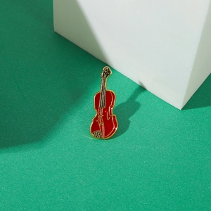 Macro shot of red enamel violin brooch with gold alloy trim on a modern texture background