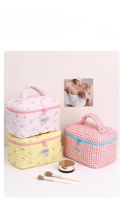 Detailed close-up of quilted plaid makeup bags with cute bows and metal zipper closure