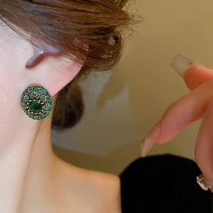 Close-up of vintage emerald stud earring with green crystals on model's ear