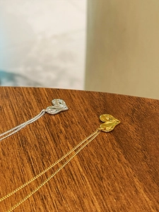Detailed view of 925 sterling silver heart necklaces in gold and silver on a wood surface