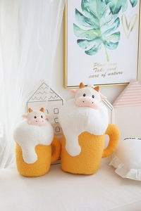 Detail of creative cow beer plush pillows in two sizes with soft textured yellow fabric