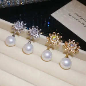 Elegant silver and gold snowflake pearl stud earrings featuring sparkling cubic zirconia