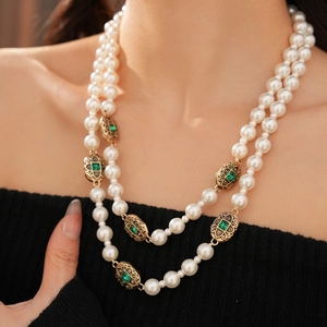 Dettaglio della collana di perle vintage a doppio filo con ciondolo di smeraldo indossata