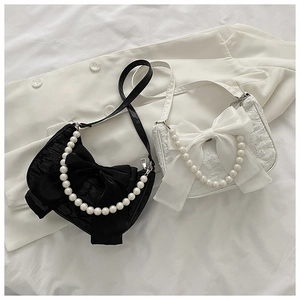 Detail of black and white textured fabric bags with bow accents and pearl handles