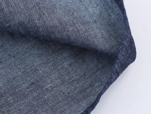 Gros plan du tissu en jean bleu foncé montrant le tissage sergé et les coutures fines